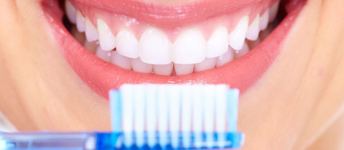 a full mouth dental implant patient smiling with a toothbrush.